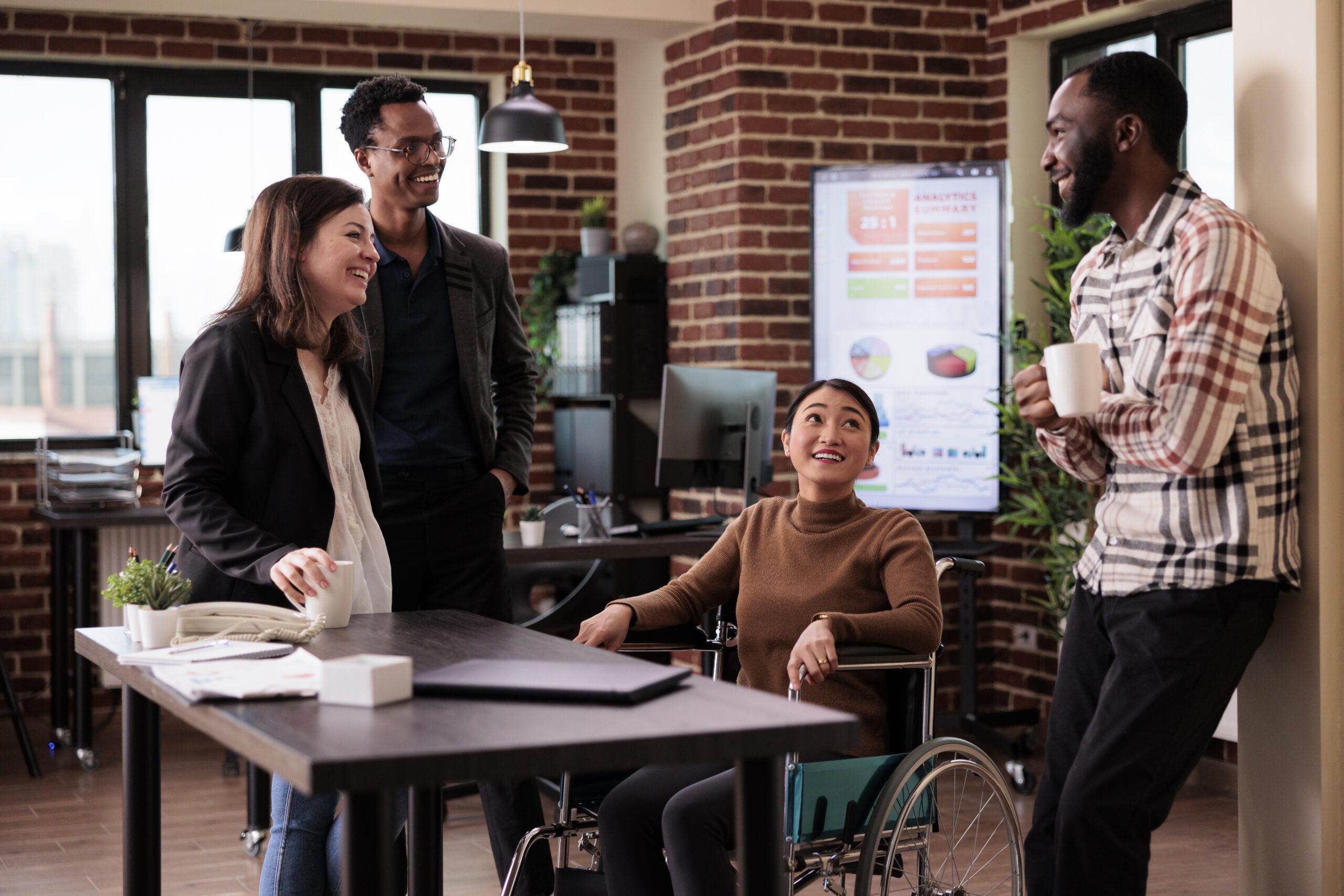 Asian woman in wheelchair and group of people laughing on job break